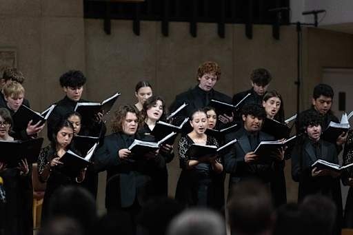 Korsangere synger flerstemt fra noter under en konsert
