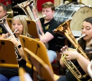 Brassband med musikere i ulike aldre under en felles øvelse