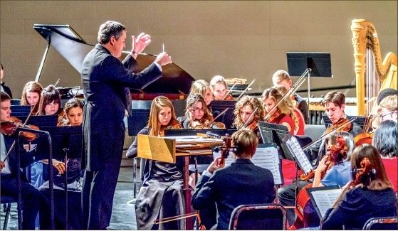 Dirigent leder et ungdomsorkester med strykere, piano og harpe